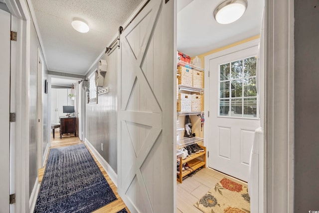 corridor featuring a barn door, light hardwood / wood-style floors, and a textured ceiling