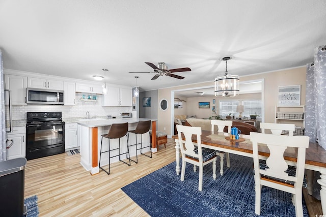 dining area featuring crown molding, light hardwood / wood-style flooring, ceiling fan with notable chandelier, and sink