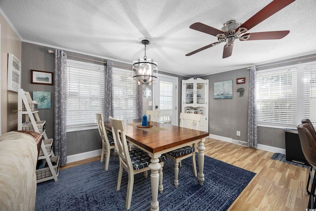 dining room with hardwood / wood-style flooring, ceiling fan with notable chandelier, crown molding, and a textured ceiling