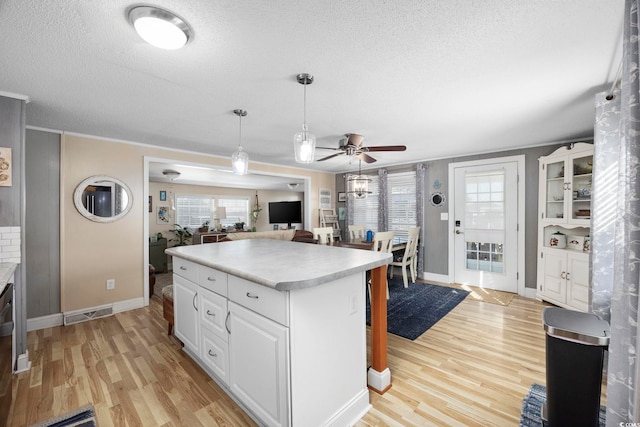 817 Wayne St, North Myrtle Beach, SC 29582 - kitchen with a textured ceiling, baseboards, light wood finished floors, ceiling fan, and a kitchen island