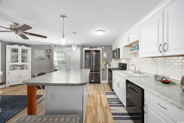 kitchen with white cabinets, a kitchen breakfast bar, sink, and black appliances