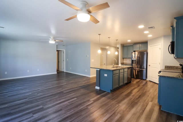 kitchen featuring pendant lighting, an island with sink, sink, range, and stainless steel fridge with ice dispenser