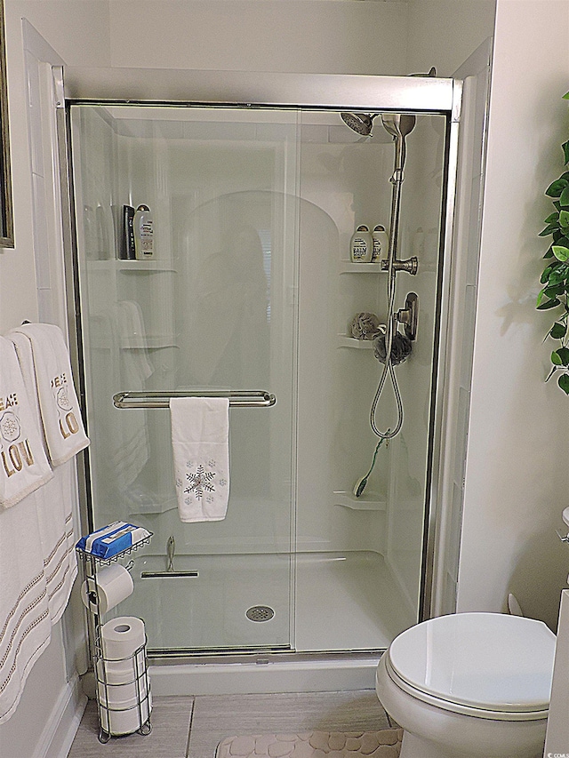 bathroom with a shower with shower door and toilet