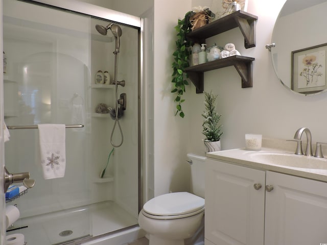 bathroom featuring vanity, toilet, and a shower with shower door