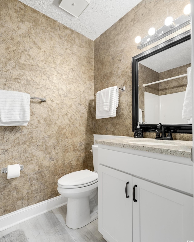 bathroom with a tile shower, vanity, a textured ceiling, wood-type flooring, and toilet