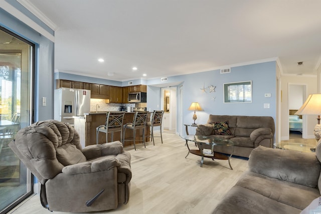 living room featuring sink, light hardwood / wood-style flooring, and ornamental molding