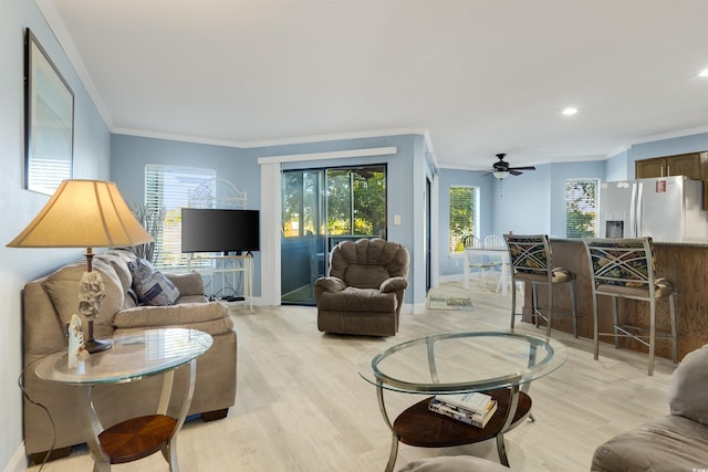 living room with light wood-type flooring, a wealth of natural light, and ornamental molding