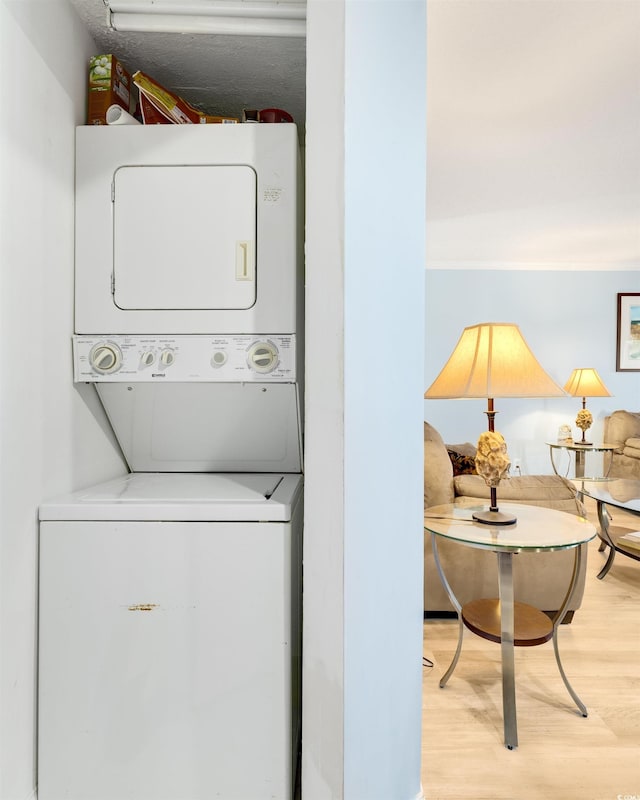 laundry room with hardwood / wood-style floors and stacked washer and clothes dryer