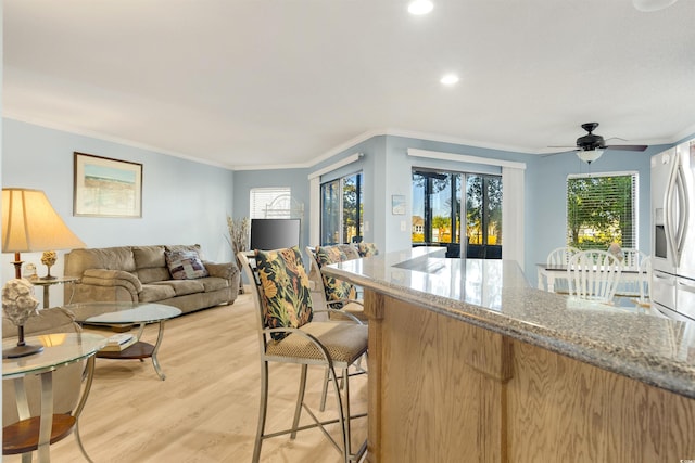 kitchen featuring light stone countertops, ceiling fan, crown molding, stainless steel fridge with ice dispenser, and light hardwood / wood-style floors