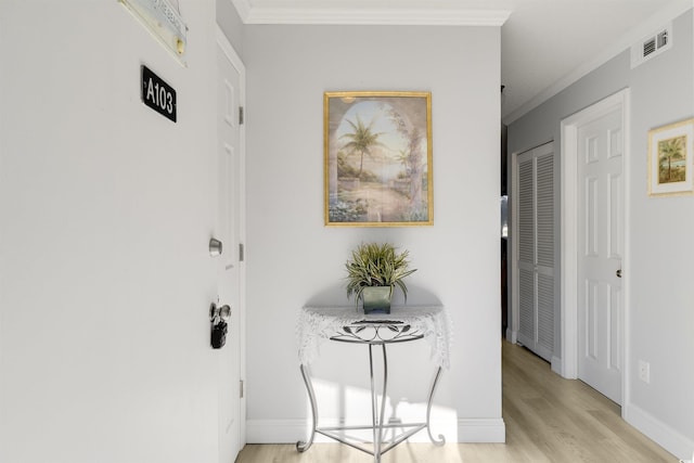 hallway with light hardwood / wood-style flooring and ornamental molding