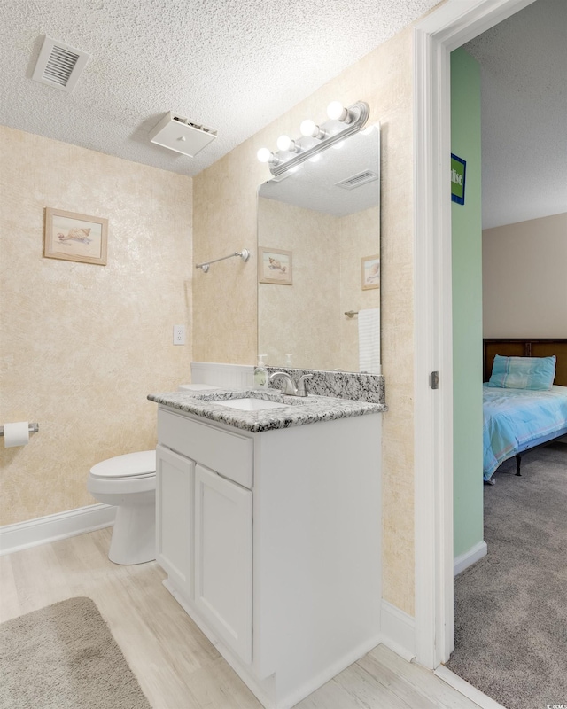 bathroom with vanity, toilet, wood-type flooring, and a textured ceiling