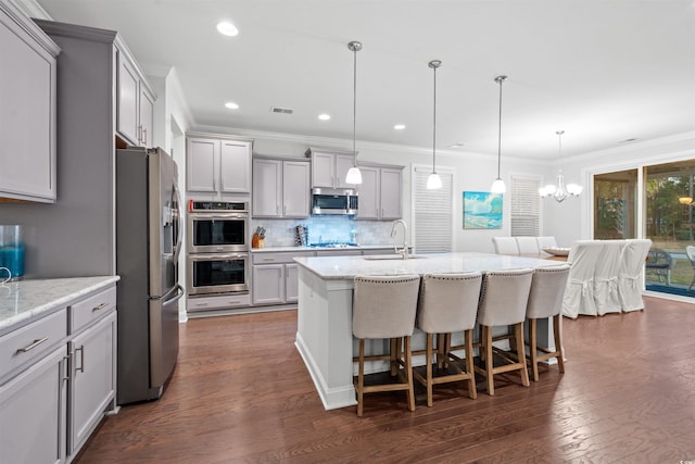 kitchen with appliances with stainless steel finishes, dark hardwood / wood-style floors, a center island with sink, and sink