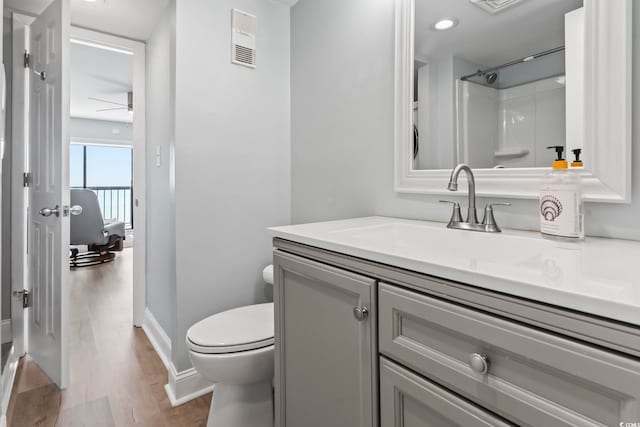 bathroom featuring walk in shower, vanity, ceiling fan, wood-type flooring, and toilet