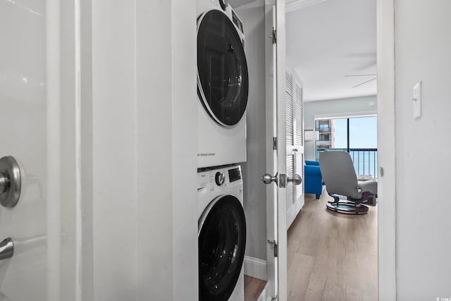 clothes washing area featuring stacked washer / dryer and wood-type flooring