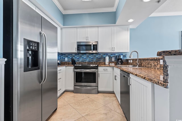 kitchen featuring white cabinets, sink, dark stone countertops, ornamental molding, and appliances with stainless steel finishes