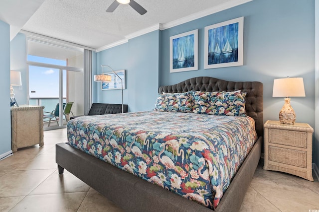 tiled bedroom with a textured ceiling, a wall of windows, ceiling fan, and crown molding