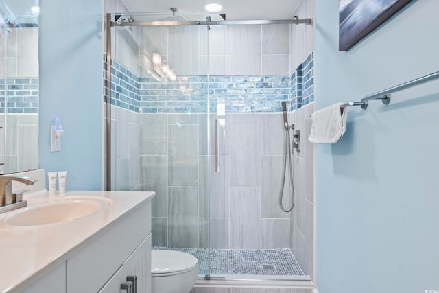 bathroom featuring vanity, a shower with shower door, and toilet