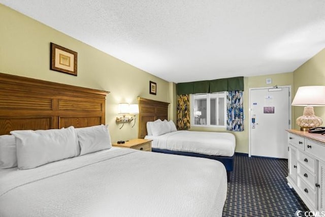 bedroom with a textured ceiling and dark colored carpet