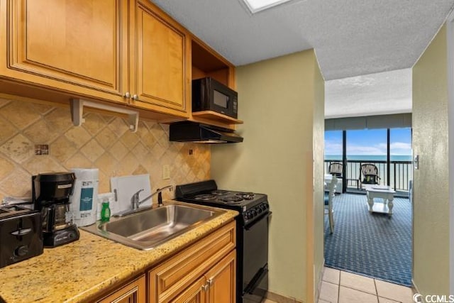 kitchen featuring black appliances, sink, light stone countertops, tasteful backsplash, and light tile patterned flooring