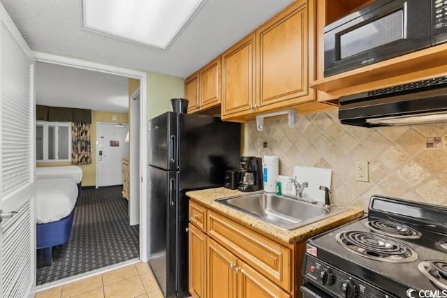 kitchen with backsplash, sink, light tile patterned floors, and black appliances