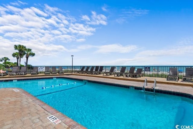 view of swimming pool with a patio area and a water view