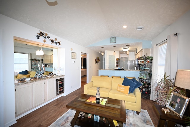 living room with lofted ceiling, dark wood-type flooring, beverage cooler, and a textured ceiling