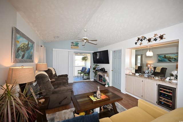 living room featuring dark wood-type flooring, a fireplace, a textured ceiling, vaulted ceiling, and beverage cooler