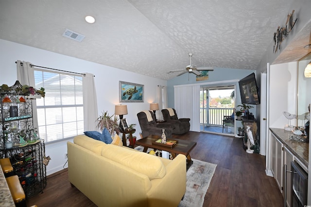 living room with ceiling fan, lofted ceiling, dark hardwood / wood-style floors, and a textured ceiling