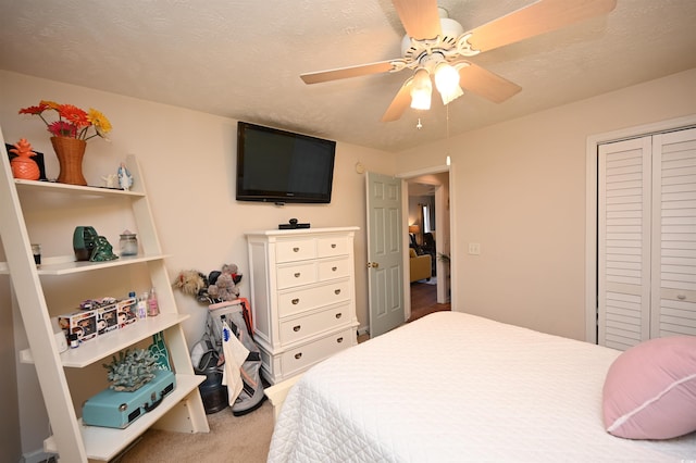 bedroom featuring ceiling fan, carpet flooring, a closet, and a textured ceiling