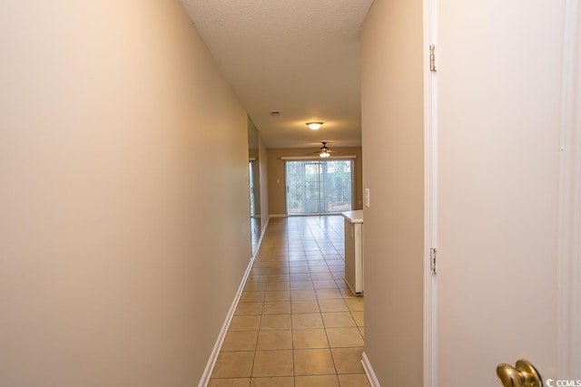 hall with light tile patterned flooring and a textured ceiling