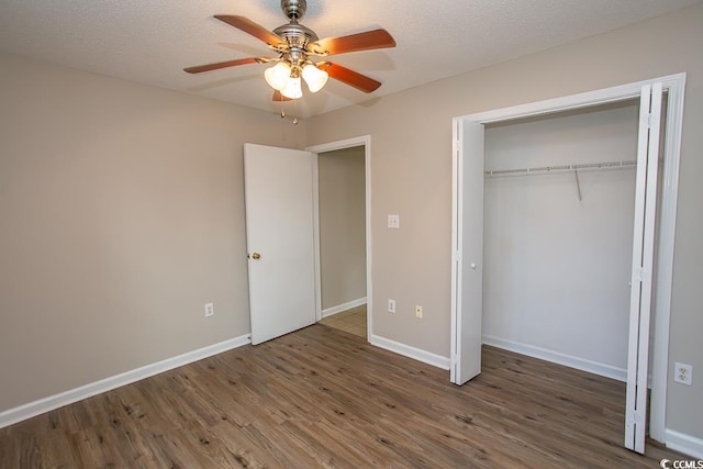 unfurnished bedroom with a closet, a textured ceiling, dark hardwood / wood-style floors, and ceiling fan