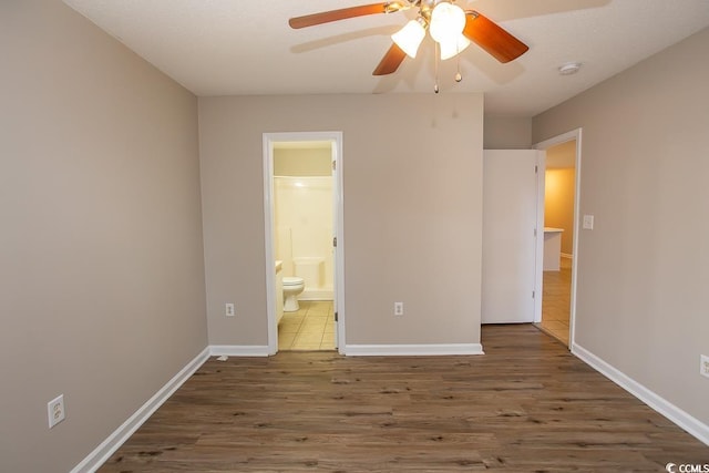 unfurnished bedroom with connected bathroom, ceiling fan, and dark wood-type flooring