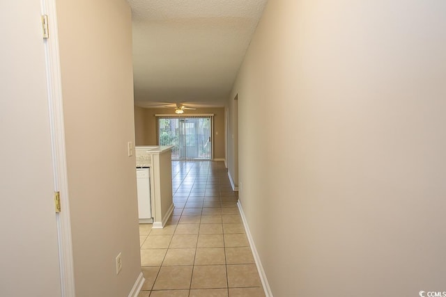 corridor featuring light tile patterned floors and a textured ceiling