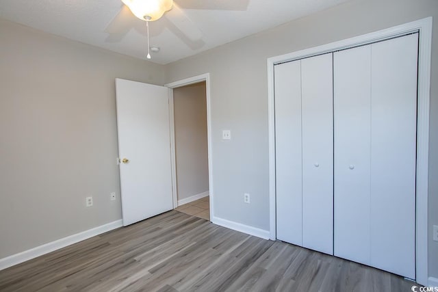 unfurnished bedroom with ceiling fan, a closet, a textured ceiling, and light wood-type flooring