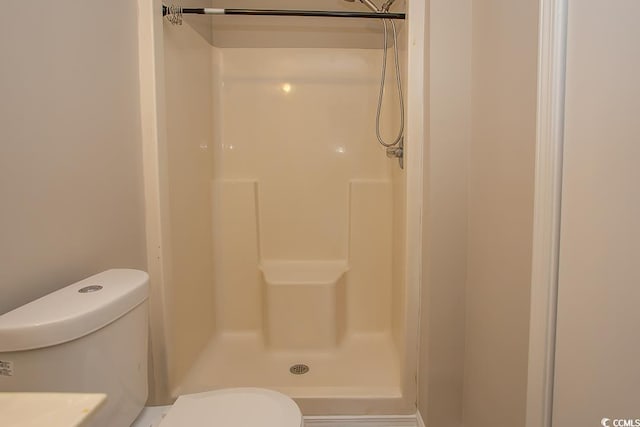 bathroom featuring walk in shower and toilet