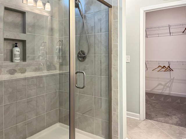 full bathroom featuring a stall shower, a spacious closet, and tile patterned floors