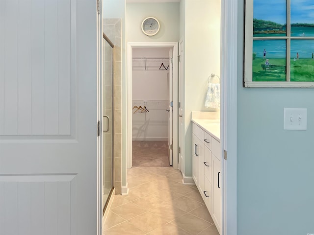 bathroom featuring a shower stall, vanity, a walk in closet, and tile patterned floors