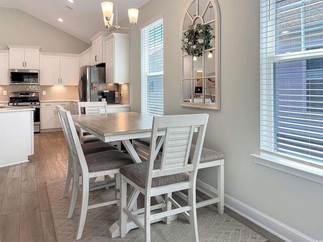 kitchen with appliances with stainless steel finishes, backsplash, sink, decorative light fixtures, and white cabinets