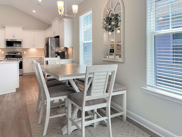 dining room with baseboards, vaulted ceiling, light wood-type flooring, a chandelier, and recessed lighting