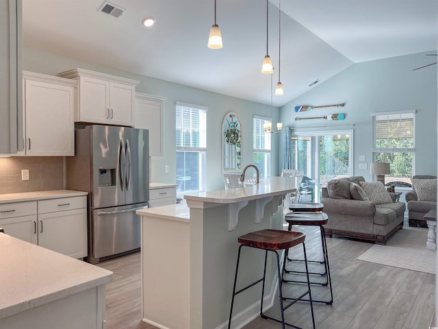 kitchen featuring visible vents, white cabinets, stainless steel fridge with ice dispenser, lofted ceiling, and light wood-style floors