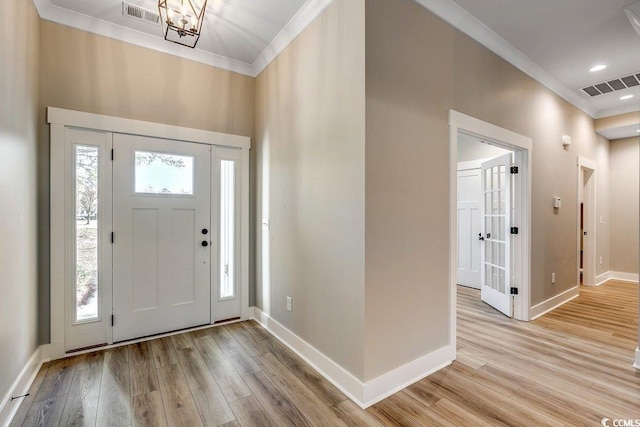 entrance foyer with an inviting chandelier, crown molding, and light hardwood / wood-style flooring