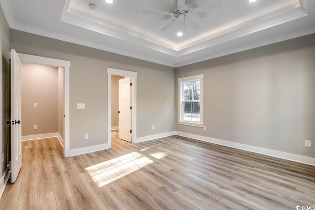 unfurnished bedroom featuring ceiling fan, ornamental molding, light hardwood / wood-style flooring, and a raised ceiling