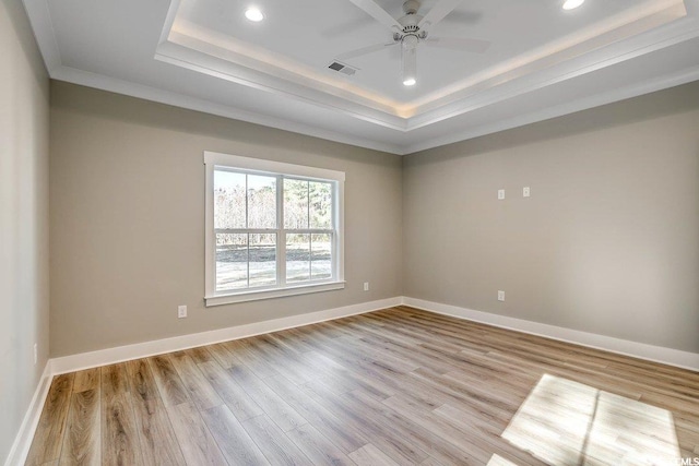 unfurnished room featuring ceiling fan, crown molding, light hardwood / wood-style flooring, and a raised ceiling