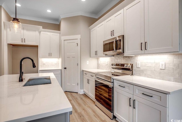 kitchen with appliances with stainless steel finishes, white cabinets, hanging light fixtures, and sink