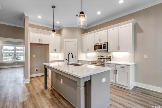 kitchen featuring white cabinetry, stainless steel appliances, a kitchen island with sink, hanging light fixtures, and sink