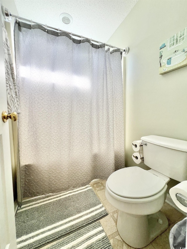 bathroom with tile patterned flooring, a shower with curtain, a textured ceiling, and toilet