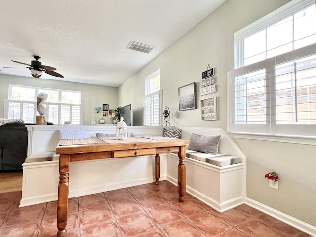 interior space with tile patterned floors, ceiling fan, breakfast area, and a textured ceiling