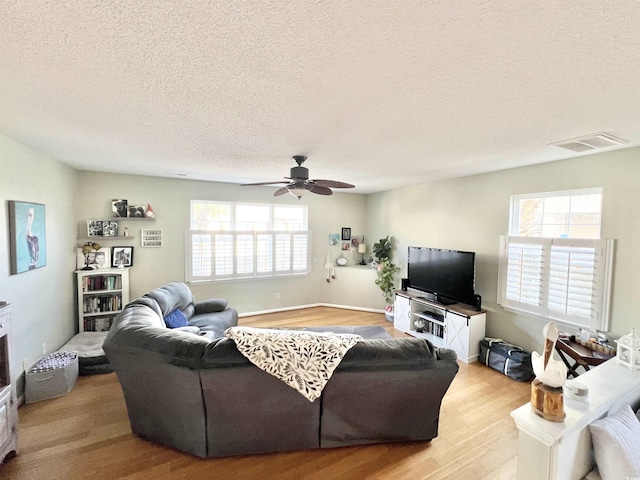 living room with ceiling fan, a healthy amount of sunlight, light wood-type flooring, and a textured ceiling