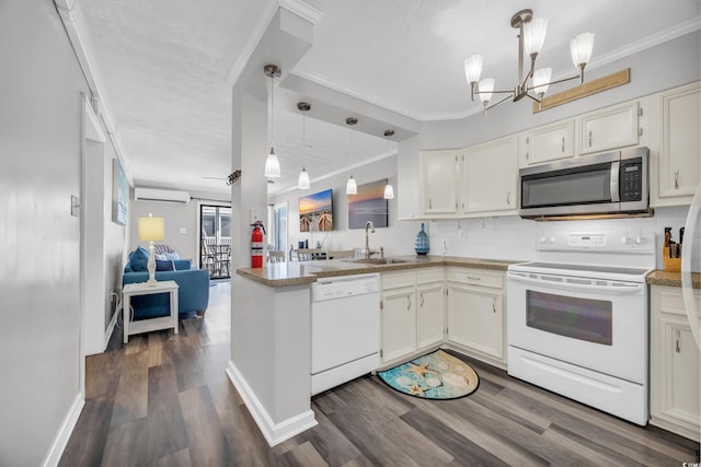 kitchen with sink, white appliances, white cabinets, decorative light fixtures, and an AC wall unit