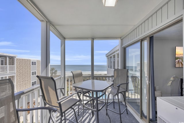 sunroom / solarium featuring a water view and a view of the beach